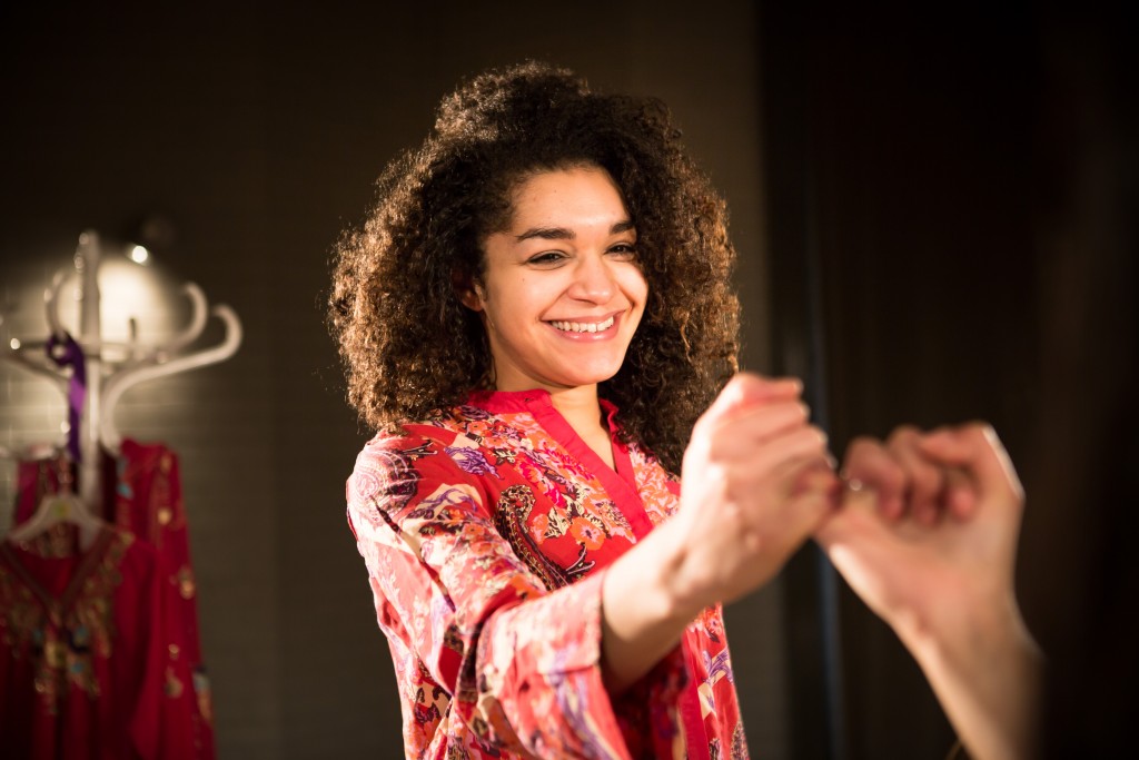 A production picture from New Vic Borderlines' All Our Daughters? A girl in a patterned top links little fingers with another person. 