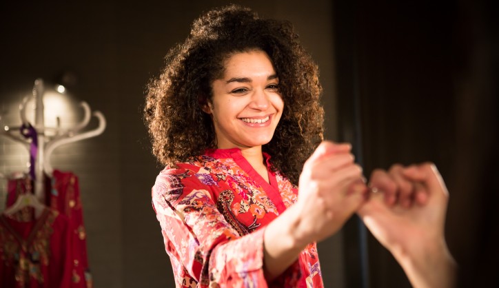 A production picture from New Vic Borderlines' All Our Daughters? A girl in a patterned top links little fingers with another person.