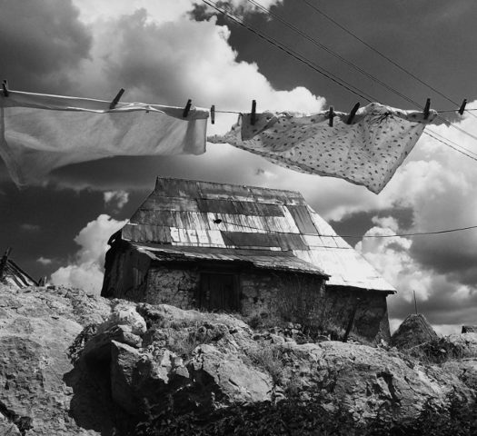 Clothes hanging on a washing line in front of a rugged landscape with houses on.
