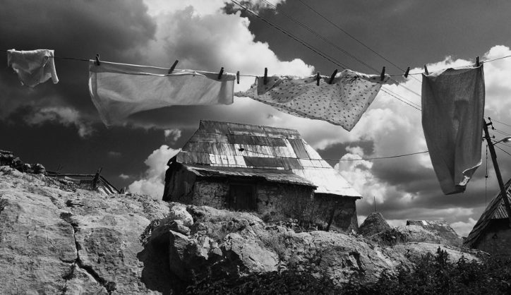 Clothes hanging on a washing line in front of a rugged landscape with houses on.