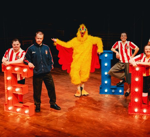 The cast of Marvellous at the New Vic theatre with the words 'Nello' in big lit-up letters on the stage.