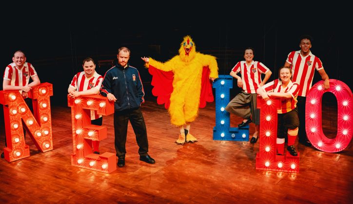 The cast of Marvellous at the New Vic theatre with the words 'Nello' in big lit-up letters on the stage.