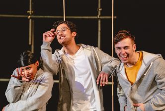 A group of young people dressed in tracksuits laugh together on a playground, in a production image from New Vic Borderlines' Stealing Dreams. Credit Andrew Billington