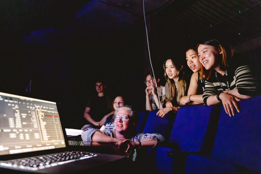 Kiln Sparks participants watch a projection on stage. In the foreground is the programme that controls the projection. Credit Andrew Billington