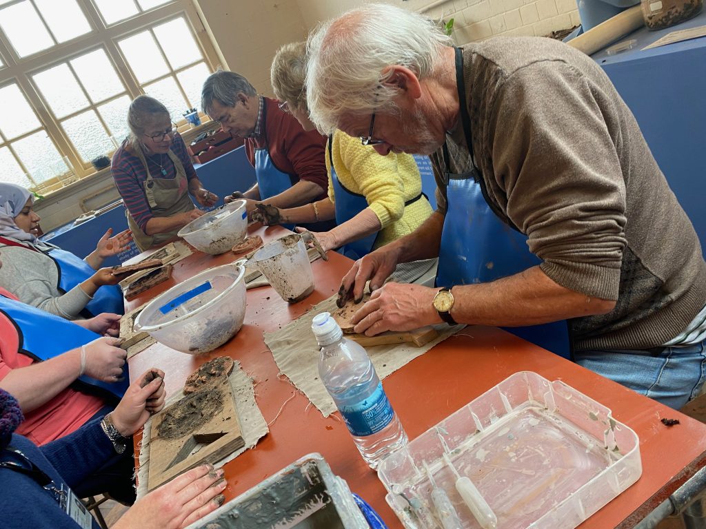 The tiles were crafted by the group at the BCB Tactile Project Space. Here they can be seen shaping them using a mould. 