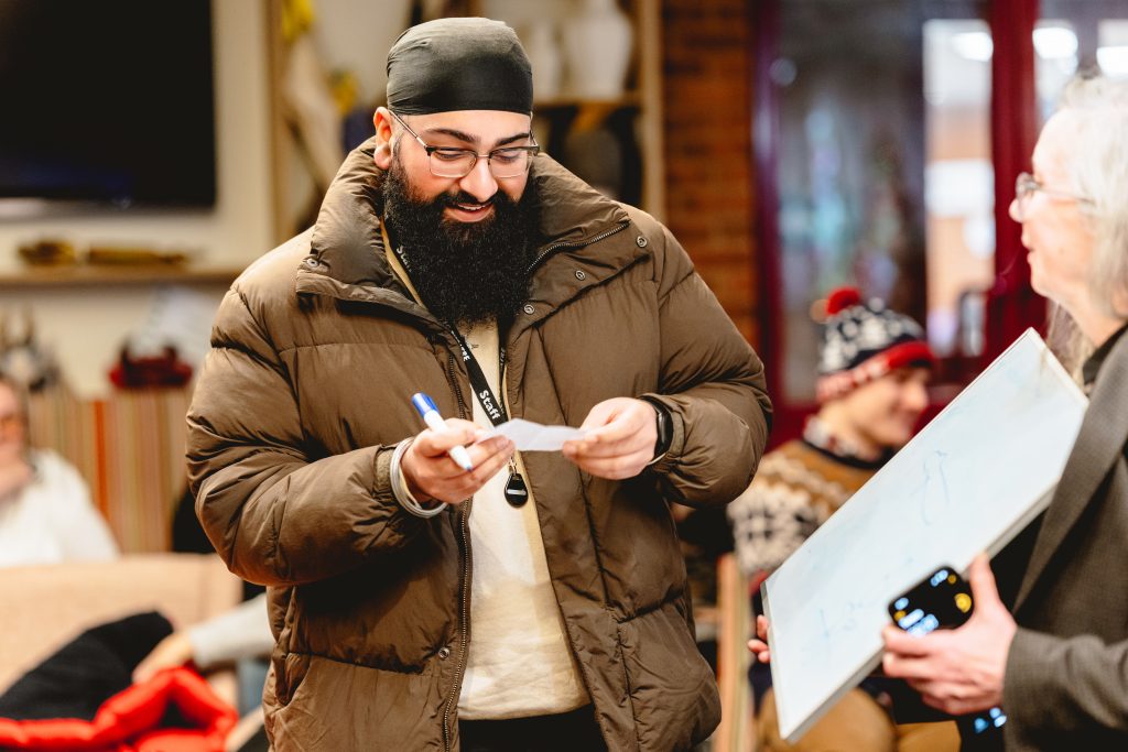 A man in a puffy jacket looks down at a charade. Picture from Next Chapter Christmas quiz night in the New Vic bar. Credit: Andrew Billington