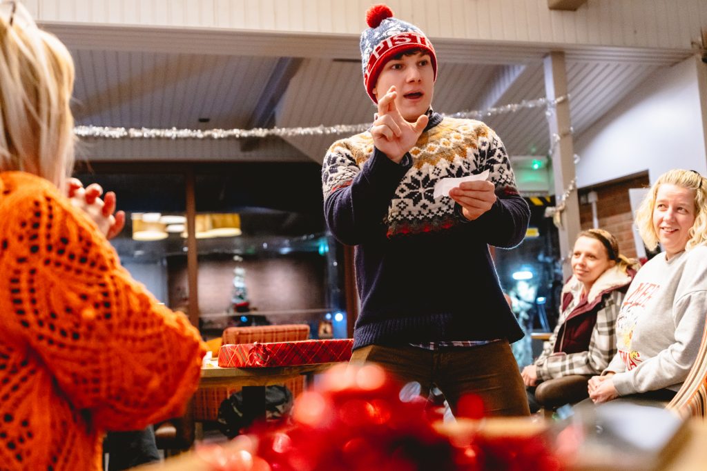 A man in a Christmas jumper and bobble hat acts out a charade. Picture from Next Chapter Christmas quiz night in the New Vic bar. Credit: Andrew Billington
