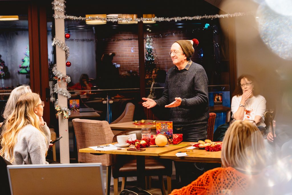 A man wearing a Christmas pudding bobble hat acts a charade while others around him guess. Picture from Next Chapter Christmas quiz night in the New Vic bar. Credit: Andrew Billington