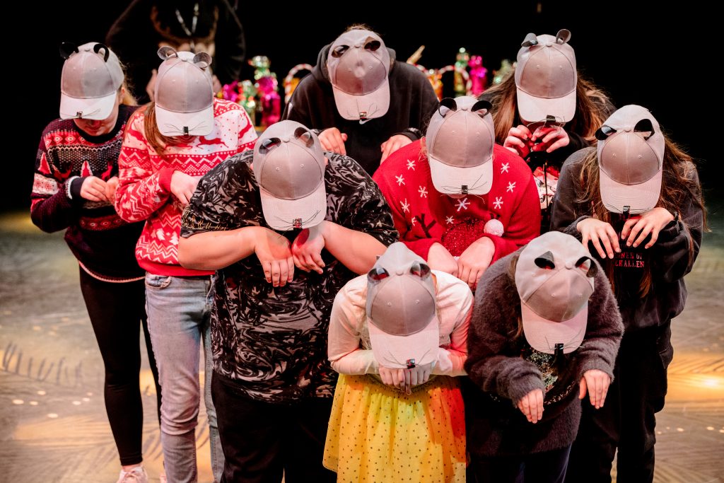 A group of young performers wear grey caps which have mouse ears and whiskers on them and embody a horde of mice. Picture from the Borderlines Young People's Theatre Company's version of The Nutcracker 2023. Credit: Andrew Billington