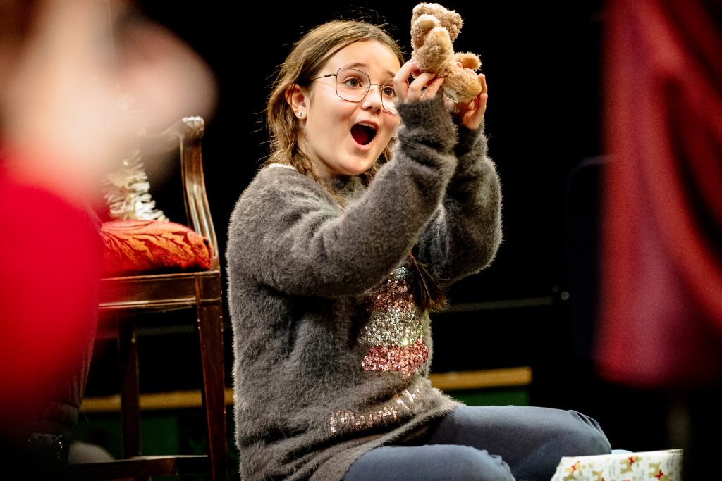 A girl holds up a teddy bear, looking excitedly at it. Picture from the Borderlines Young People's Theatre Company's version of The Nutcracker 2023. Credit: Andrew Billington