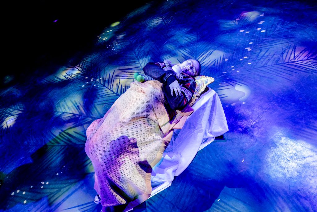 A girl sleeps holding a doll. Around her the atmosphere is icy and blue. Picture from the Strathcross version of The Nutcracker 2023. Credit: Andrew Billington