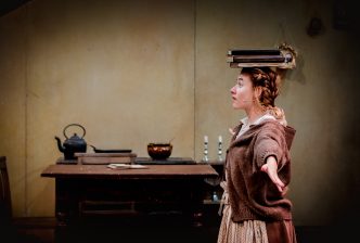 Ariella stands with her arms out, balancing a pile of books on her head. Credit: Andrew Billington