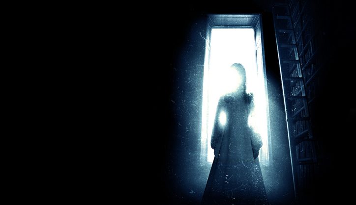 A shadowy figure stands in a doorway in the promotional image for The Haunting play
